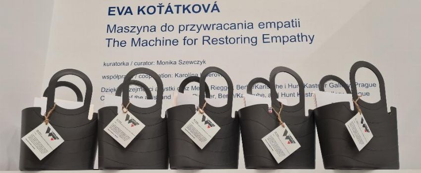 Na ladzie stoją szare koszyki z materiałami i zadaniami. W tle napis: Eva Kotatkowa "Maszyna do przywracania empatii".