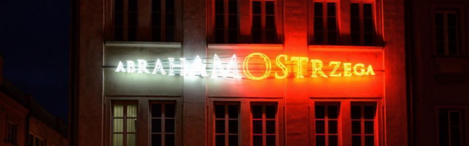 neon w postaci napisu na biało świeci się słowo Abraham a na czerwono słowo ostrzega